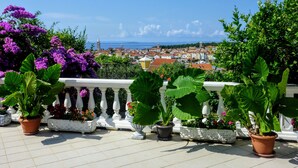A balcony with potted plants and a view of a coastal town. - Apartment With View (Rab)