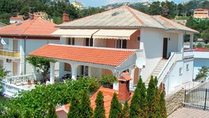 A two-story building with a red-tiled roof, white walls, and a balcony. - Apartment With View (Rab)