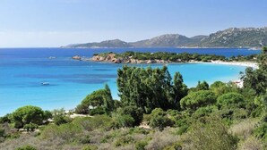 A coastal landscape with clear blue waters, a sandy beach, and dense greenery. - Stone villa with heated pool close to the most beautiful beaches! (Figari)
