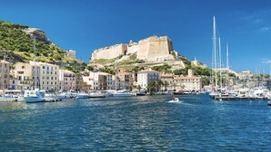 A coastal town with a historic fort on a hill, boats in the harbor, and buildings along the waterfront. - Stone villa with heated pool close to the most beautiful beaches! (Figari)