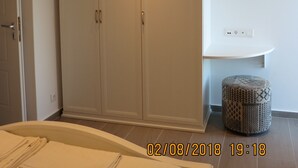 A bedroom with a large wardrobe, a bedside table, and a small ottoman. - Room-andoni's House in Pitrofos Andros i (Andros)