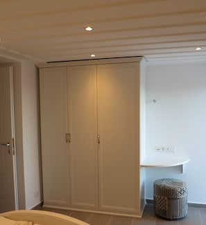 A bedroom with a large wardrobe, a bedside table, and a small ottoman. - Room-andoni's House in Pitrofos Andros i (Andros)