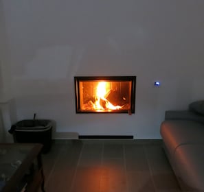 A living room with a fireplace, a sofa, and a trash bin. - Room-andoni's House in Pitrofos Andros i (Andros)
