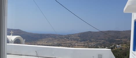 A view from a window overlooking a landscape with hills and a clear sky.