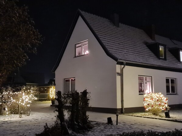 A house with a sloped roof, a visible chimney, and a snow-covered ground.