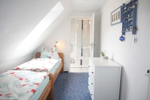 Ein Schlafzimmer mit Bett, Kommode, Ablagefläche mit Dekoration und einem Oberlicht.