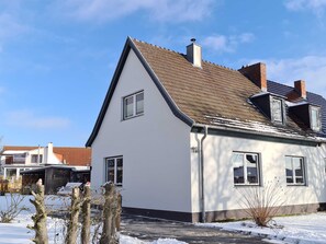 Ein modernes, zweistöckiges Haus mit einem geneigten Dach, einem Schornstein und einem sichtbaren Fenster.