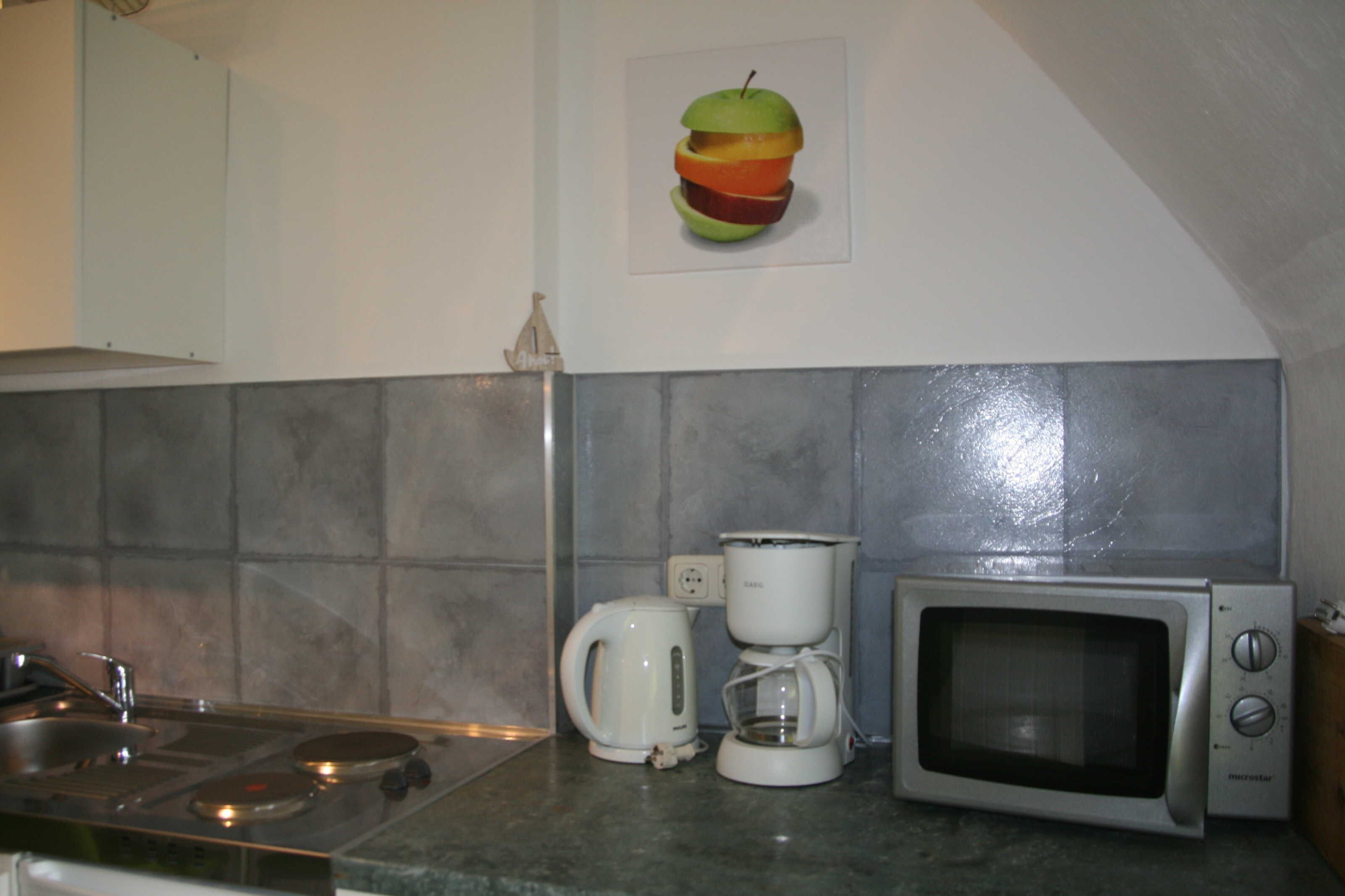 A kitchen with a stove, coffee maker, and microwave.