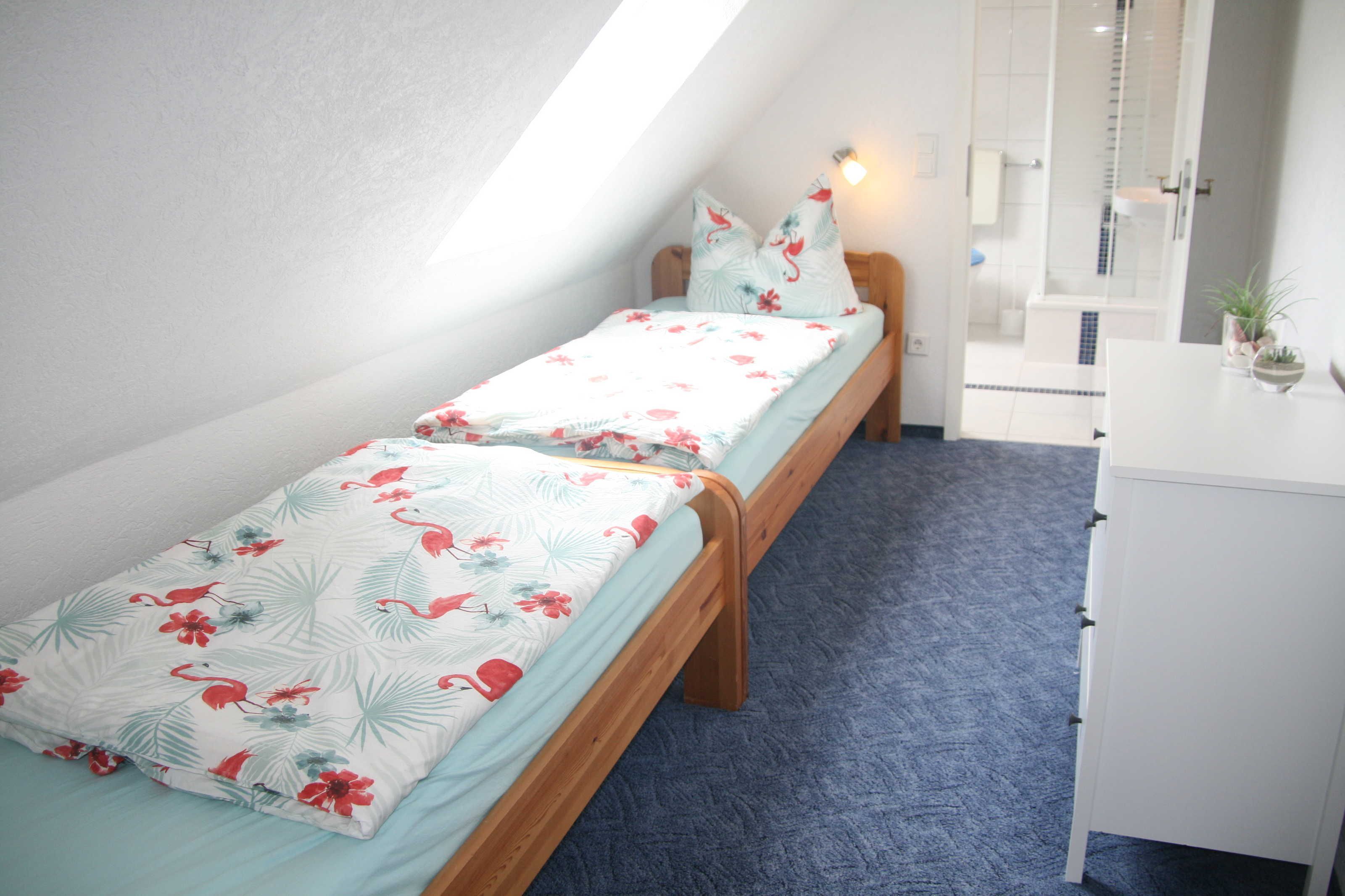 A bedroom with two single beds, a white dresser, and a shower area.