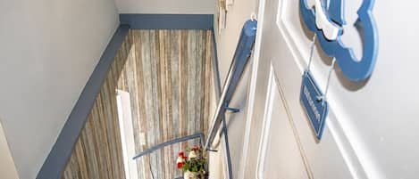 Eine Treppe mit Holzboden, einem blauen Geländer und einem an der Wand befestigten Schild.