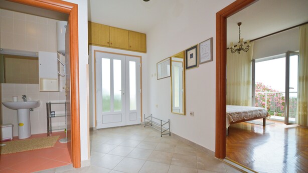Um quarto com uma cama, uma janela, um espelho e uma porta.