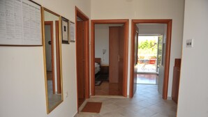 Corredor com portas de madeira que dão para um quarto e uma varanda.