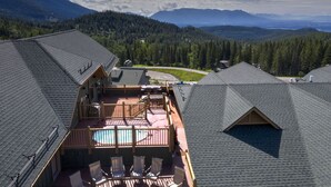 A rooftop with a swimming pool, wooden deck, and a view of a forested valley. - Top floor ski condo with direct ski in and out. Hiking and biking too! Hot tub (Whitefish)