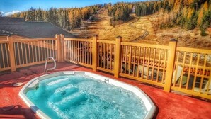 A hot tub on a deck with a view of a forested hillside. - Top floor ski condo with direct ski in and out. Hiking and biking too! Hot tub (Whitefish)
