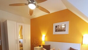 A hotel room with two beds, a ceiling fan, a bedside table with a lamp, and a framed picture on the wall. - Living Above The Roofs Of Cochem (Cochem)
