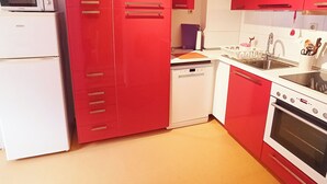 A kitchen with red cabinets, a white refrigerator, a microwave, a dishwasher, and a stove. - Living Above The Roofs Of Cochem (Cochem)