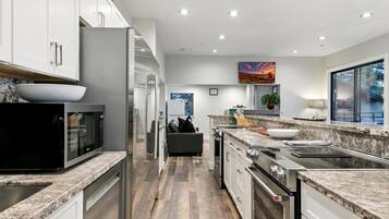 Cozinha moderna com bancadas de granito, eletrodomésticos de aço inoxidável e vista para o exterior.
