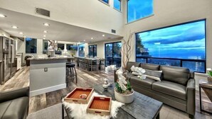 A spacious living area with a kitchen, large windows, and a view of the city.