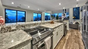 A modern kitchen with a large island, built-in oven, and a view of the ocean.