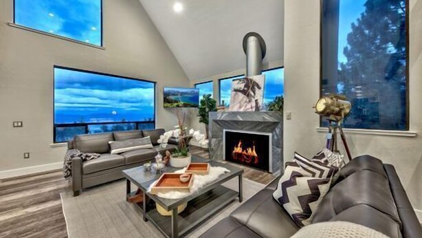 A modern living room with a fireplace, large windows, and a cozy seating area.
