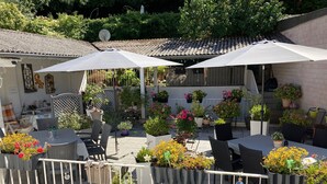 An outdoor patio area with tables and chairs, surrounded by potted plants and umbrellas. - Living in the Historic Cochem Old Town (Cochem)