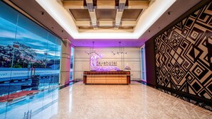 A hotel reception area with a modern design, a reception desk, and a large window with a view.