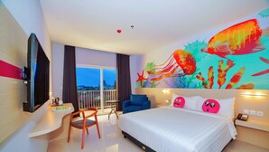 A hotel room with a large bed, a desk with a chair, a television, and a mural of fish on the wall.