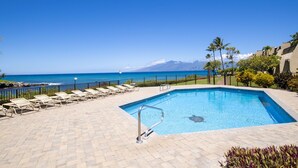 A swimming pool with lounge chairs and a view of the ocean.