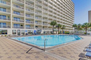 A hotel with a large pool area, multiple balconies, and a modern architectural design.