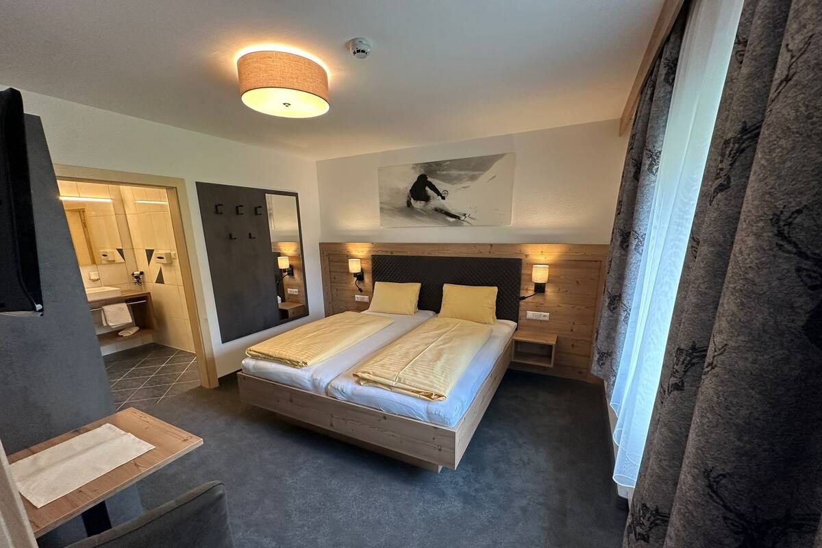 Una camera d'albergo con un letto grande, comodini, uno specchio e un quadro appeso al muro.