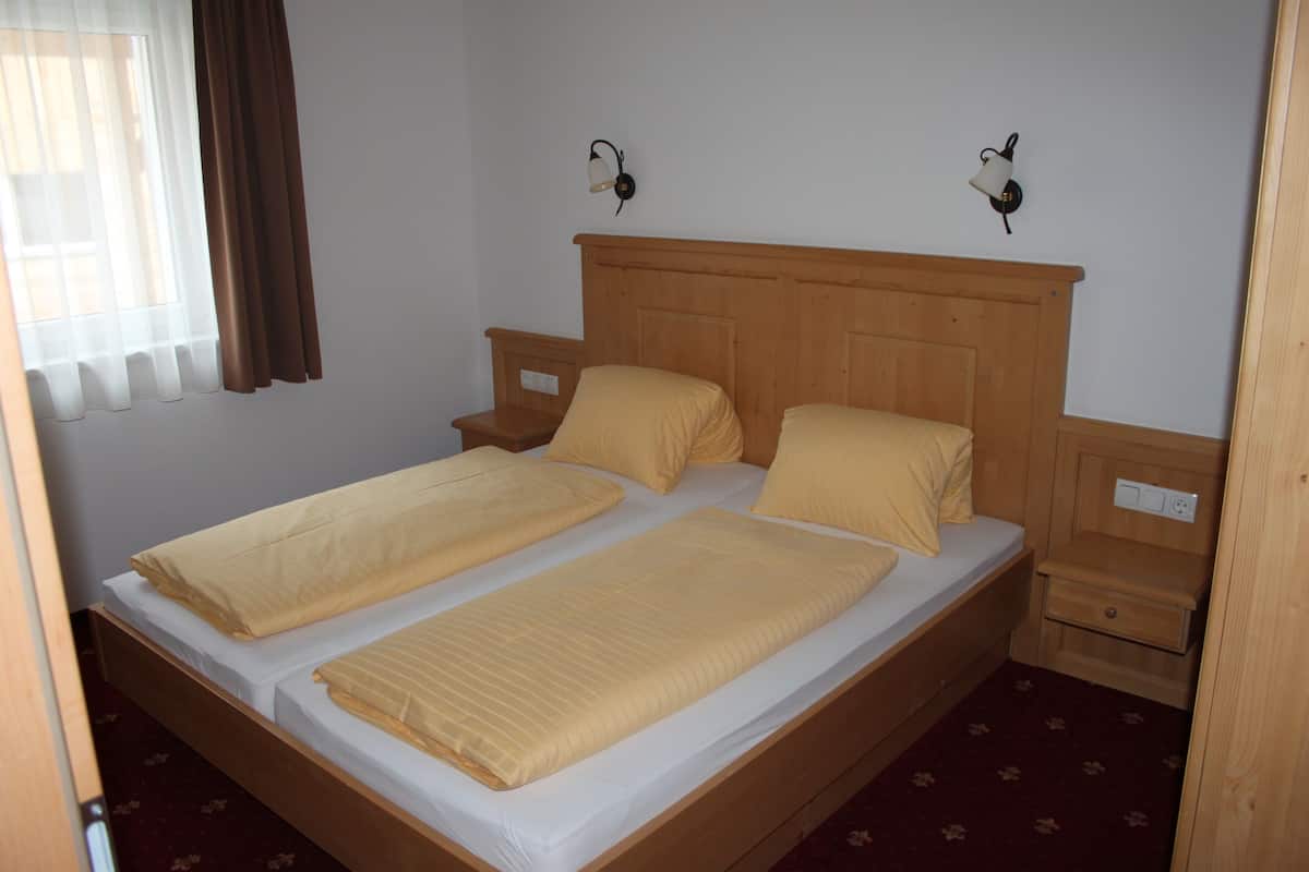 Un letto matrimoniale con testiera in legno, due comodini e una finestra con tende.