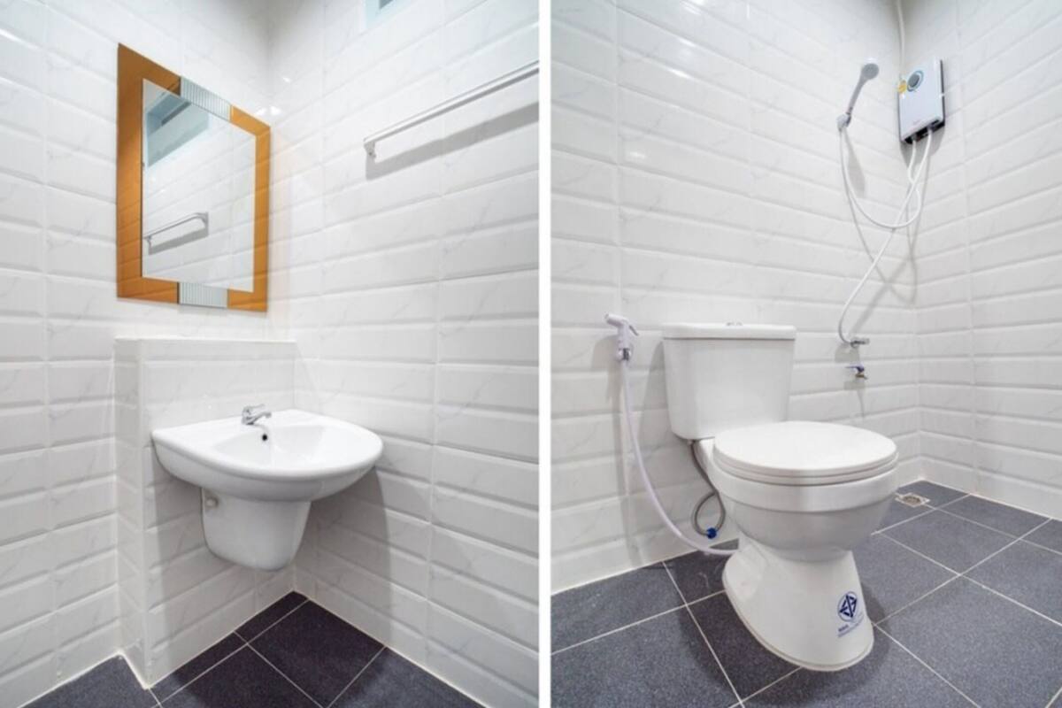 A bathroom with white tiled walls, a white sink, and a toilet.