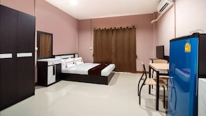 Ein Schlafzimmer mit Bett, Schreibtisch, Stuhl, Kleiderschrank und einem Kühlschrank.