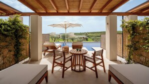 A covered outdoor seating area with a pool view, wooden furniture, and a pergola.