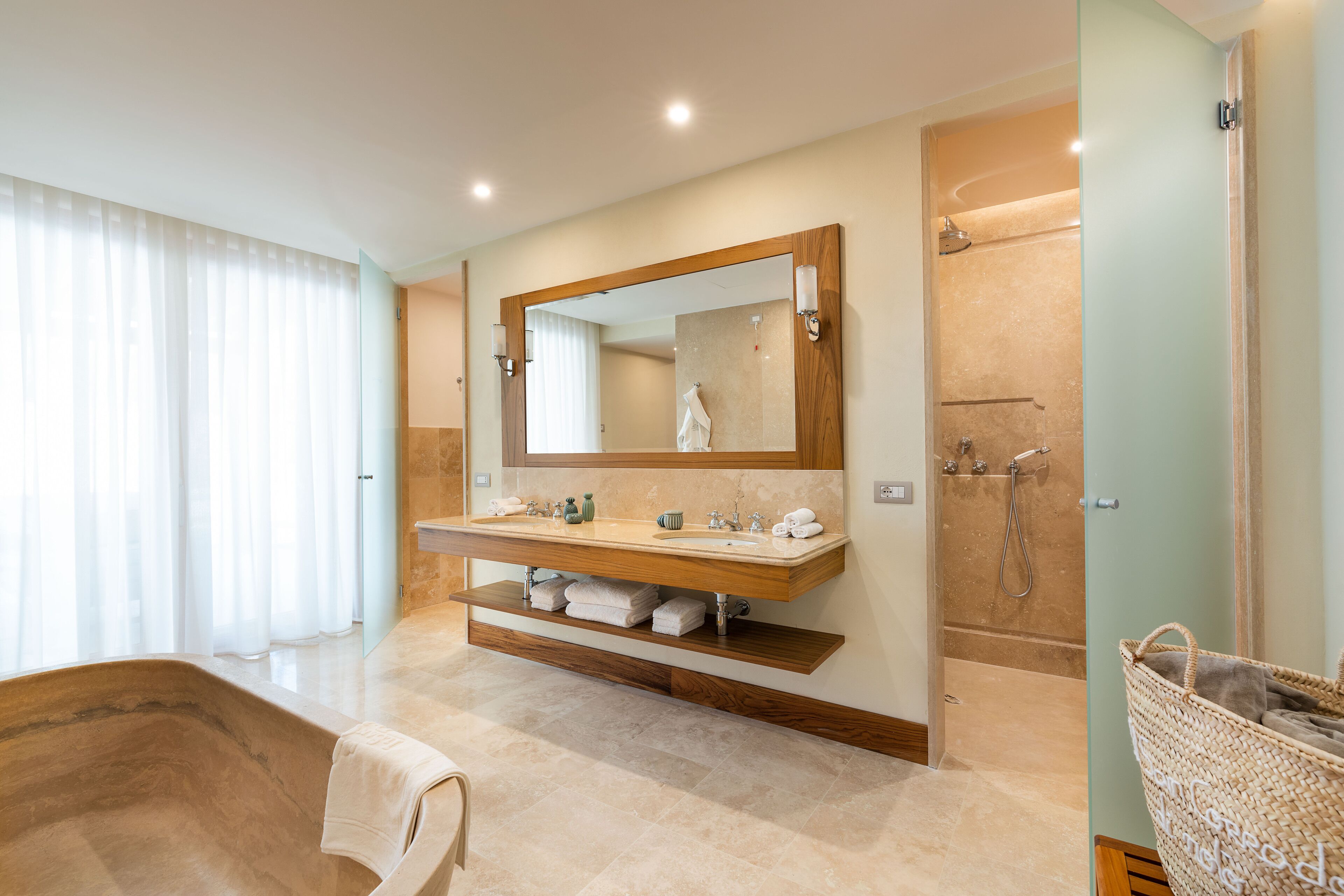 A modern bathroom with a large mirror, a bathtub, a shower, and a vanity with a sink and towel racks.