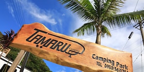Señal de madera del Parque de Camping Tamaru con información de contacto.