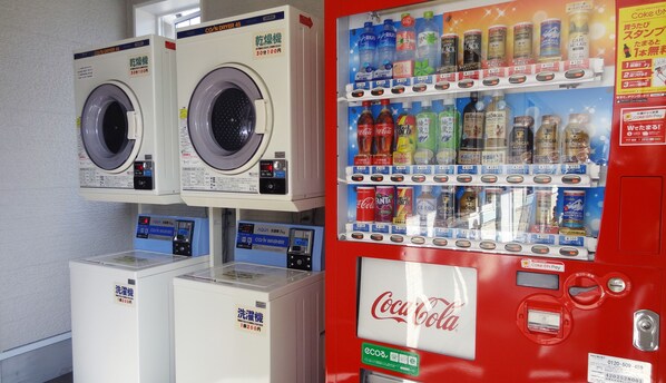 A laundromat with two washing machines and a Coca-Cola vending machine.