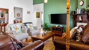 Un salon avec des canapés à rayures, une table basse en bois, un téléviseur et un mur vert.