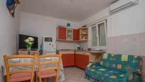 Een kleine keuken met een eettafel, stoelen, een bank en een televisie.