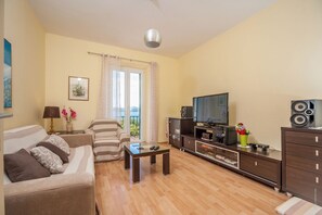 Een woonkamer met een bank, een salontafel, een televisie en een kast.