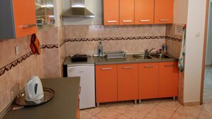 A compact kitchen with orange cabinets, a stainless steel sink, and a Koncar refrigerator. - Room-stay in the Center of Zadar at Peni (Zadar)