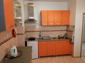 A compact kitchen with orange cabinets, a stainless steel sink, and a Koncar refrigerator. - Room-stay in the Center of Zadar at Peni (Zadar)