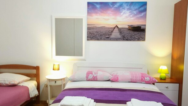 Habitación de hotel con una cama, dos mesitas de noche, un armario de madera y un cuadro colgado en la pared.
