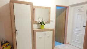 Habitación con armario, espejo, planta en maceta y puerta con letrero de 'No fumar'.