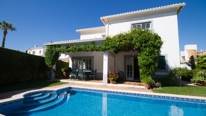 A two-story house with a swimming pool in the foreground.