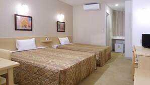 Habitación de hotel con dos camas, un escritorio, un televisor y un refrigerador pequeño.