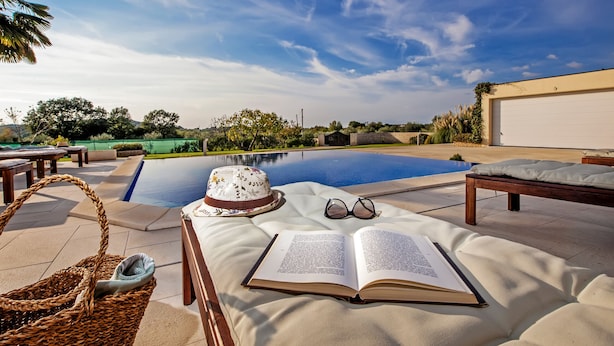 A poolside area with a lounge chair, a hat, a pair of glasses, and an open book. - Villa Montericco (Rovinj)