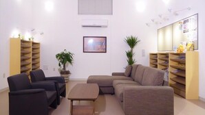 A living room with a sofa, chairs, a coffee table, and shelves with books and decorative items. - Family Lodge Hatagoya Kobe Suma (Kobe)