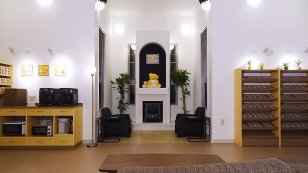 A living room with a fireplace, two chairs, a coffee machine, and a bookshelf. - Family Lodge Hatagoya Kobe Suma (Kobe)