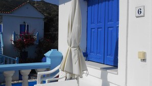 A white building with a blue door and a white table with an umbrella. - Meltemia Studio Samos No6 Pefkos (Samos)